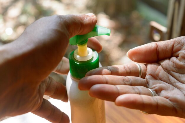 Close-up di una mano che usa una bottiglia di disinfettante di plastica