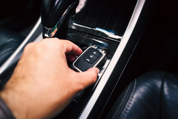 Close up di una mano del conducente che tiene un telecomando di un'auto senza chiave di ingresso remoto sul pannello di trasmissione automatica