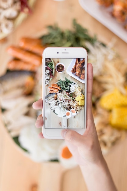 Close-up di una mano tagliata che fotografa il cibo con uno smartphone
