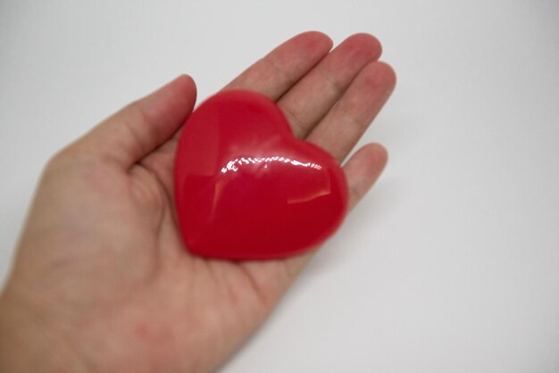 Close-up di una mano tagliata che tiene la forma di un cuore su sfondo bianco
