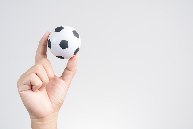 Close-up di una palla da calcio giocattolo tenuta in mano sullo sfondo grigio