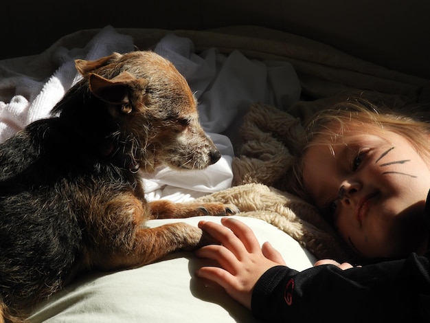 Close-up di una ragazza carina sdraiata sul letto con un cane