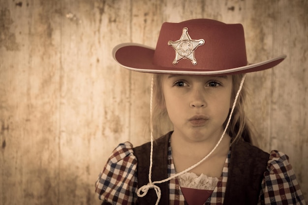 Close-up di una ragazza che indossa un cappello da cowboy contro il muro