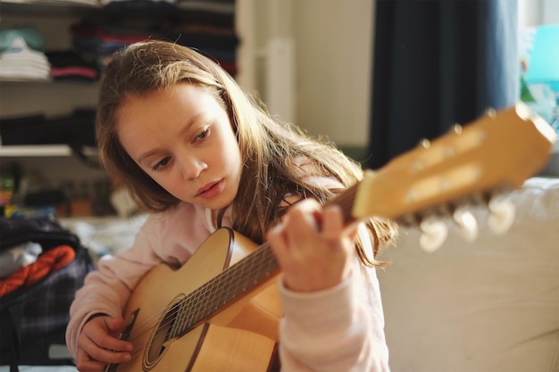 Close-up di una ragazza che suona la chitarra a casa