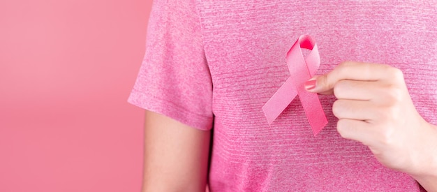 Close-up di una ragazza che tiene un fiore rosa su uno sfondo rosa