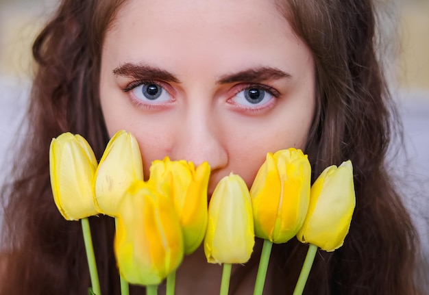 Close-up di una ragazza occhi con tulipani gialli primavera umore riflessivo