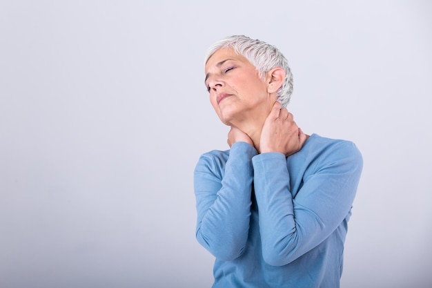 Close-up di una signora anziana triste con mal di collo, una donna anziana con sindrome da dolore cronico, fibromialgia, che soffre di mal di collo acuti.