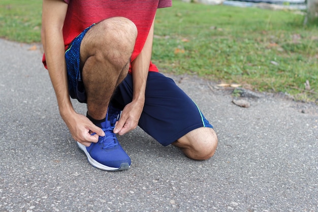 Close-up di uno sportivo che lega le scarpe da ginnastica alle scarpe da corsa prima di allenarsi a correre