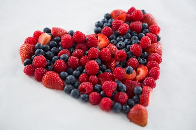 Close-up di vari frutti che formano una forma di cuore su sfondo bianco