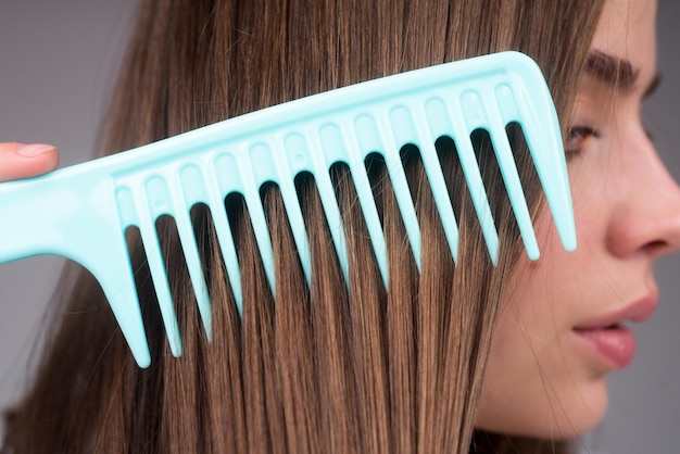 Close up donna che pettina i capelli macro pettine per capelli pettina il concetto di cura dei capelli dei capelli