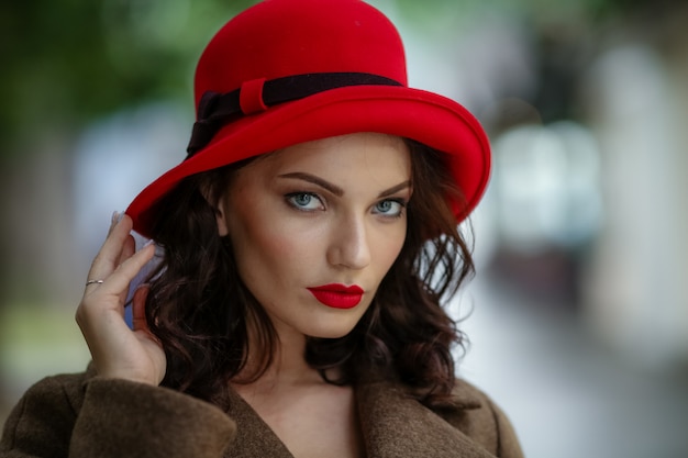 Close-up donna di 28-30 anni con i capelli scuri in un cappotto elegante e accessori rossi