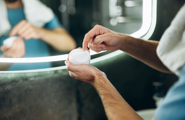 Close up foto uomo con crema viso idratante in bagno la mattina presto.