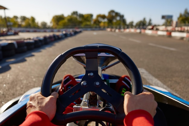 Close-up gokart racer guida auto sportiva concentrarsi sulle mani che tengono il volante