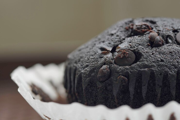 Photo close up of a chocolate chip on a chocolate muffin over white background