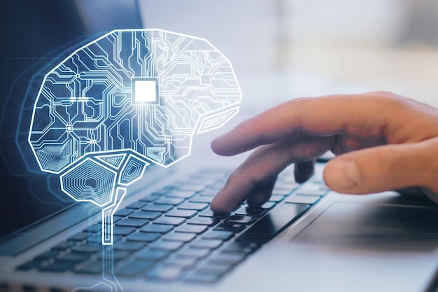 Close up of male hand using laptop with creative glowing AI brain hologram and circuit on blurry office background Artificial intelligence and innovation concept