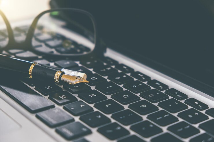 Photo close-up of pen and eyeglasses on laptop keyboard