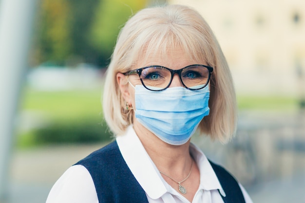 close-up photo Senior donna che indossa una maschera medica protettiva sul viso in cortile