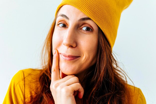 Close up ritratto di un hipster ragazza adolescente dito in bocca con cappello giallo sulla testa