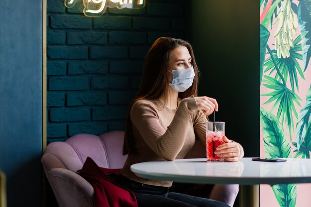 Close up ritratto di una donna caucasica che indossa una maschera medica e in piedi in strada contro un caffè