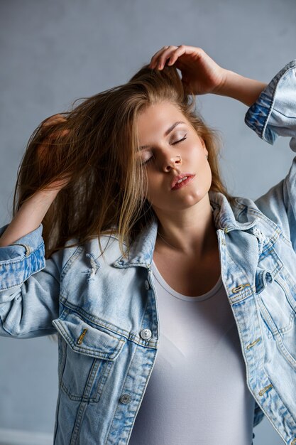 Close up ritratto di una giovane e bella donna. Foto triste emotiva di una ragazza. Vestito con una maglietta bianca e una giacca di jeans