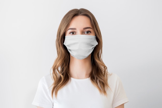 Close up ritratto di una giovane ragazza che indossa la maschera protettiva medica isolata su uno sfondo bianco