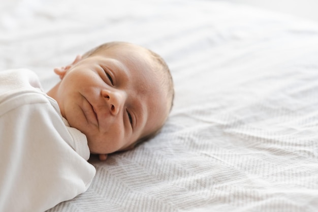 Close up sorridente caucasico peloso brunet carino neonato guardando cameraone o bambino di due settimane