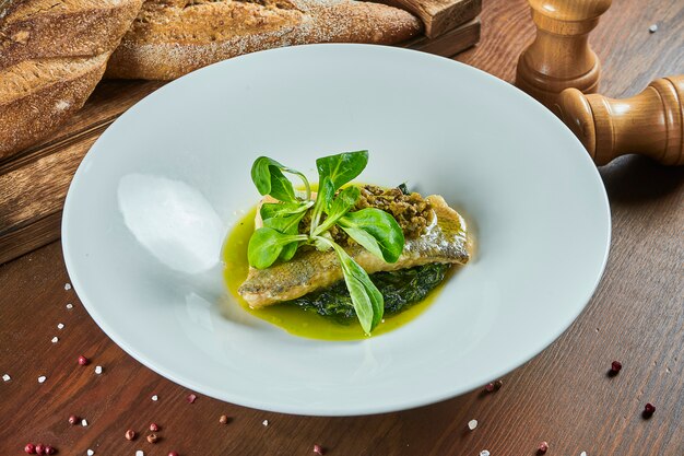 Close up su gourmet Filetto di pesce persico alla griglia su un cuscino di spinaci in umido con salsa verde. Cibo salutare. Cibo del ristorante.