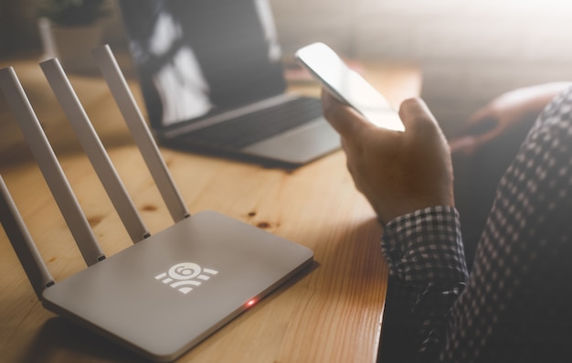Close up sul router wireless e sulla persona che usa lo smatphone