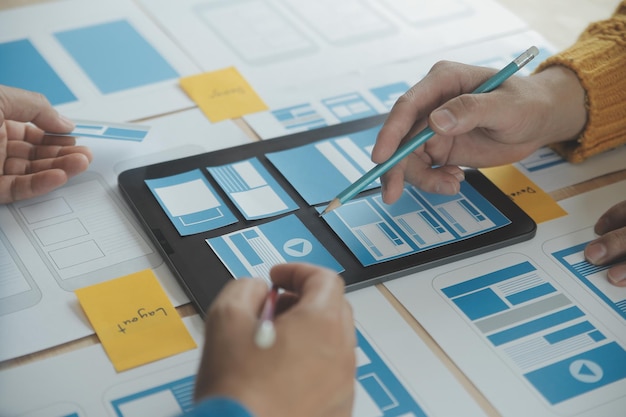 close up ux developer and ui designer brainstorming about mobile app interface wireframe design on table with customer breif and color code at modern officecreative digital development agency