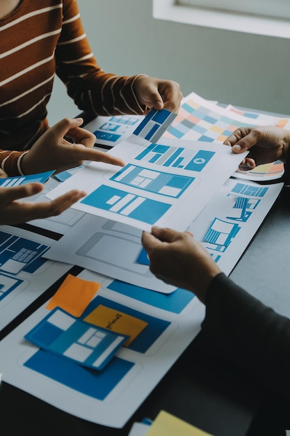 close up ux developer and ui designer brainstorming about mobile app interface wireframe design on table with customer breif and color code at modern officecreative digital development agency
