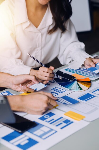 Close up ux developer e ui designer brainstorming sull'interfaccia dell'app mobile wireframe design sul tavolo con breif del cliente e codice colore in un ufficio modernoagenzia di sviluppo digitale creativa