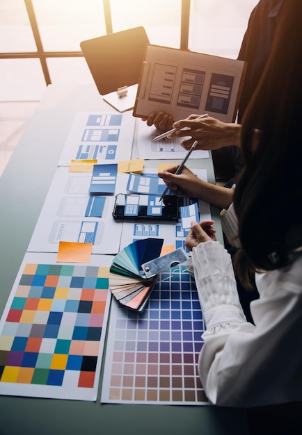 Close up ux developer e ui designer brainstorming sull'interfaccia dell'app mobile wireframe design sul tavolo con breif del cliente e codice colore in un ufficio modernoagenzia di sviluppo digitale creativa