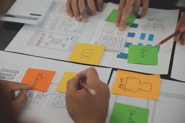 Close up ux developer e ui designer brainstorming sull'interfaccia dell'app mobile wireframe design sul tavolo con breif del cliente e codice colore in un ufficio modernoagenzia di sviluppo digitale creativa