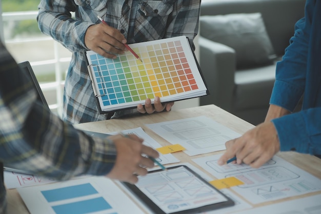 Close up ux developer e ui designer brainstorming sulla progettazione wireframe dell'interfaccia dell'app mobile sul tavolo con breif del cliente e codice colore presso l'ufficio modernoAgenzia di sviluppo digitale creativo
