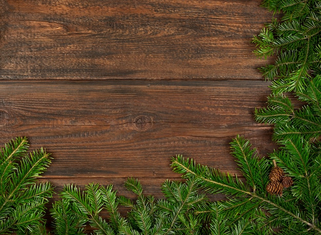 Close up verde fresco di abete rosso o pino rami di albero di Natale con coni su tavole di legno marrone scuro sfondo con copia spazio