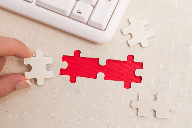 Close-Up White Jigsaw Pattern Puzzle Pieces da collegare con l'ultimo pezzo mancante posizionato su uno sfondo piatto con texture diverse e accessori per forniture di carta