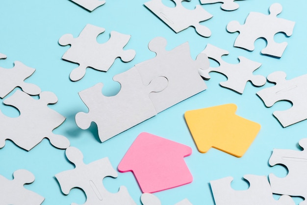 Close-Up White Jigsaw Pattern Puzzle Pieces da collegare con l'ultimo pezzo mancante posizionato su uno sfondo piatto con texture diverse e accessori per forniture di carta