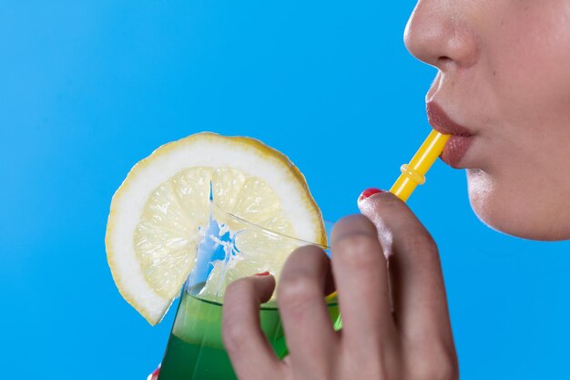 Closeup delle labbra femminili mentre bevono una bevanda alcolica fredda verde attraverso una cannuccia