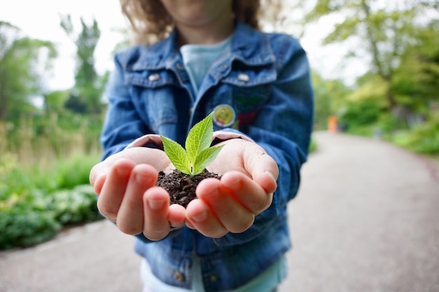 Closeup delle mani di un bambino che tiene il terreno con un germoglio, salva il concetto del mondo