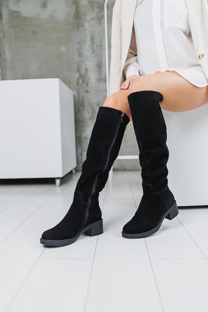 Closeup di gambe femminili in stivali di camoscio in pelle nera alta Scarpe invernali da donna Stivali da donna caldi Scarpe moderne da donna