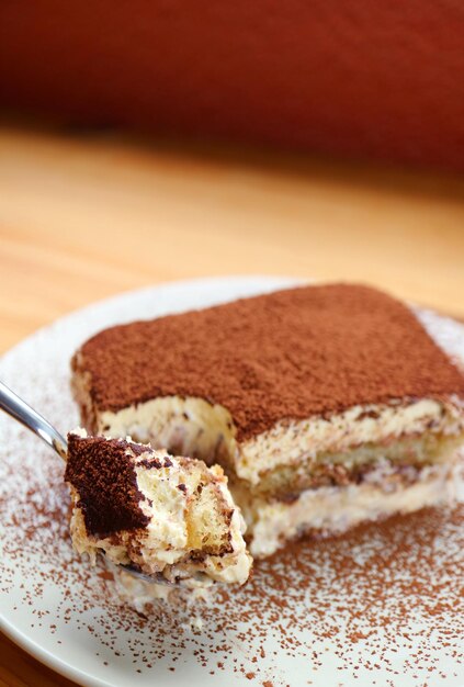 Closeup di un cucchiaio che raccoglie l'acqua della bocca Tiramisu Cake