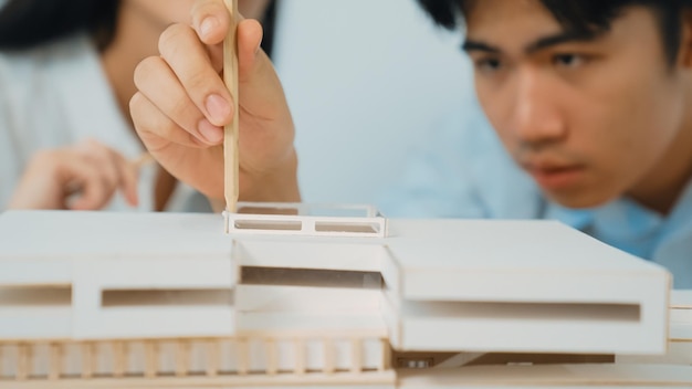 Closeup di un giovane team di architetti professionisti che lavorano insieme per usare la matita per testare la durata del modello di casa sulla costruzione della casa Design creativo e concetto di lavoro di squadra Focus on hand Immaculate