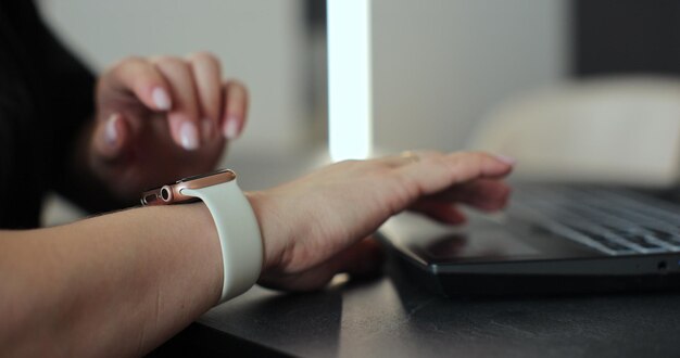 Closeup di una donna che tocca lo schermo di un orologio intelligente che scorre sul display del dispositivo in ufficio