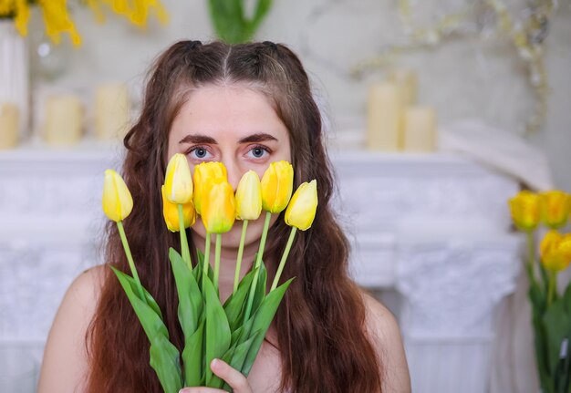 Closeup di una giovane ragazza con i capelli lunghi che tiene un bouquet di tulipani gialli