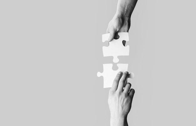 Closeup hands of man connecting jigsaw puzzle Two hands trying to connect couple puzzle with yellow background Hand connecting jigsaw puzzle Man hands connecting couple puzzle piece