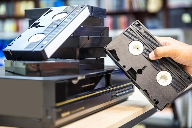 Closeup mano sceglie cassetta video VHS vecchio stile retro e premere il pulsante