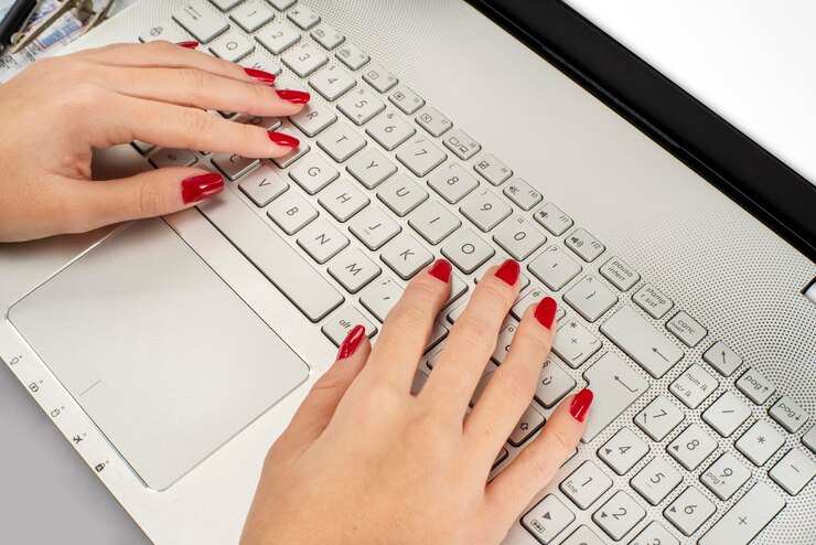 Photo closeup of girls hands on a laptop with red nails