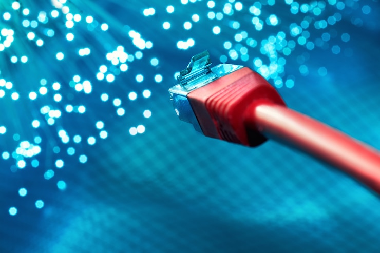Photo closeup on the end of red optical fiber network cable on blue background