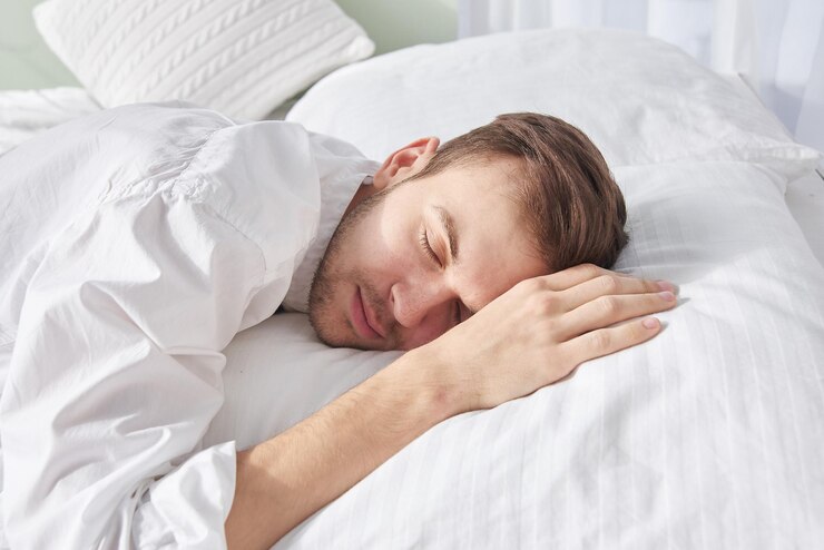 Closeup portrait of sleeping brunette man on white pillow
