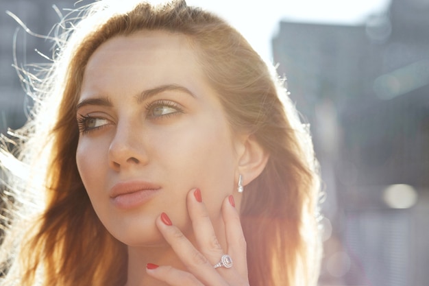 Closeup ritratto di bella donna bionda con i capelli lunghi in posa sullo sfondo della città. Spazio per il testo